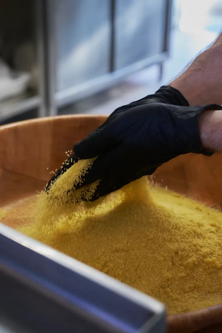 La semoule de couscous roulée à la main dans un grand plat de bois