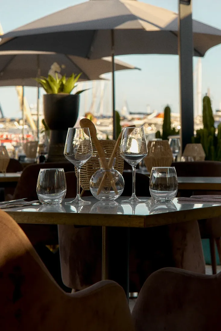 Une table dressée en terrasse au coucher du soleil, face au port